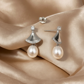 Pearl earrings with silver accents on a beige fabric background
