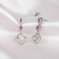 Pair of diamond earrings with pink gemstones on a light background