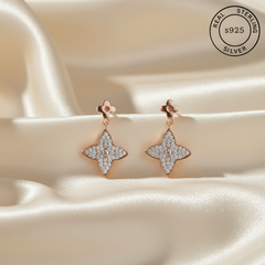 Rose gold earrings with diamond-like stones featuring 'Real Sterling Silver' stamp.
