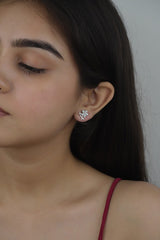 A person wearing 925 sterling silver blush bloom stud earrings with rose gold finish and a small pearl accent.