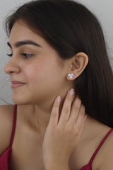 A woman wearing 925 sterling silver sparkling stud earrings with a floral design.