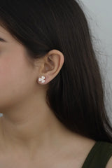 A person wearing 925 sterling silver rose gold sparkling stud earrings with a floral design.