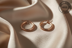 Rose gold hoop earrings on beige fabric with 'Real Sterling Silver 925' stamp.