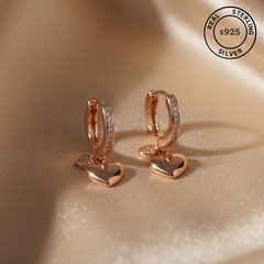 Rose gold hoop earrings with heart pendants featuring 'Real Sterling Silver 925' stamp.