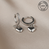 Silver hoop earrings with heart charms featuring 'Real Sterling Silver' stamp.