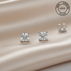 Pair of silver square-cut stud earrings on a satin surface with 'Real Sterling Silver 925' stamp.