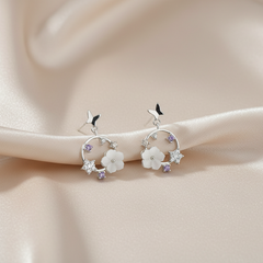 Silver earrings with floral designs on a soft beige background
