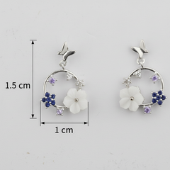 Pair of earrings with floral design and measurements on a light gray background