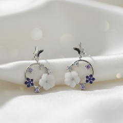 Pair of silver earrings with floral designs on a white background