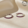 Silver hoop earrings with pink gemstones on a beige surface, featuring 'Real Sterling Silver' certification.
