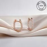 Rose gold hoop earrings with AAA+ CZ on a beige fabric background, featuring 'Real Sterling Silver 925' stamp.