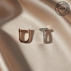 Gold 'U' and silver 'T' earrings on a beige fabric background with 'Real Sterling Silver 925' stamp.