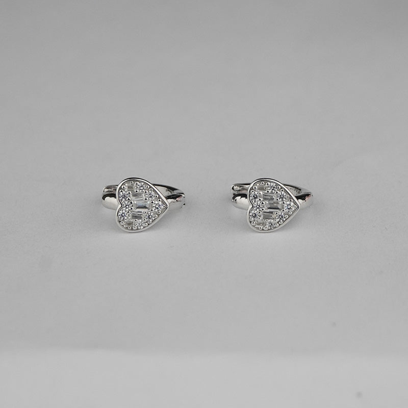 Heart-shaped silver earrings on a gray background