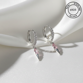 Silver hoop earrings with pink gemstones on a white surface, featuring 'Real Sterling Silver' label.
