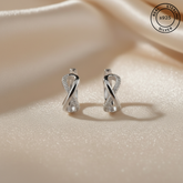 Silver earrings on a beige fabric background with 'Real Sterling Silver' stamp.