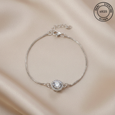 Silver bracelet with a diamond on a beige fabric background, featuring 'Real Sterling Silver' certification.