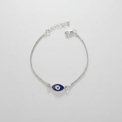 Silver bracelet with a blue evil eye charm on a gray background