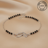 Black beaded bracelet with silver clasp on a beige background, featuring 'Real Sterling Silver' stamp.