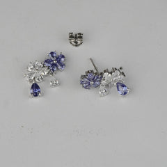 Pair of silver earrings with purple gemstones on a gray background