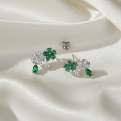 Pair of earrings with green gemstones on a white fabric background