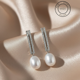 Silver Pearl Drop Danglers
with silver accents on a soft pink fabric background