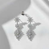 Pair of silver floral earrings on a white surface
