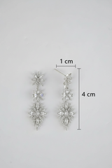 Silver earrings with measurement details on a gray background