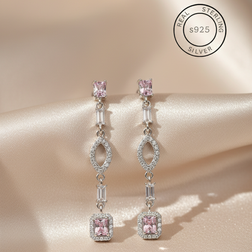 Silver earrings with pink gemstones on a beige fabric background, featuring 'Real Sterling Silver S925' label.