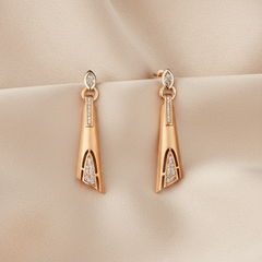 Rose gold earrings with diamond accents on a beige fabric