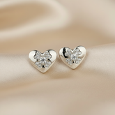 Heart-shaped earrings with floral designs on a beige fabric background