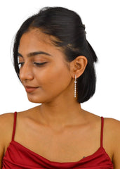 A woman wearing silver hoop earrings with a heart design, looking to the side.