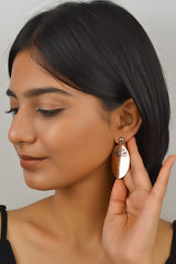 A women showcasing a sterling silver oval dangle earring with a rose gold finish.