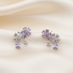 Pair of purple and clear crystal earrings on a soft beige background