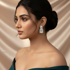 Woman wearing a pair of diamond earrings against a beige background