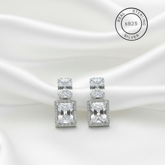 Silver earrings with clear zircon stones on a white background, featuring 'Real Sterling Silver' label.