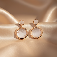 RoseGold and white circular earrings on a beige fabric background