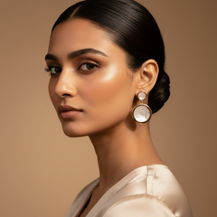 Woman wearing large, round earrings against a beige background