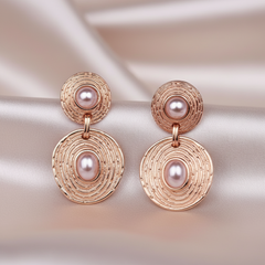 Rose gold earrings with pearl beads on a soft fabric background