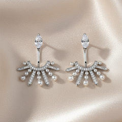 Pair of silver earrings with pearls and crystals on a beige background