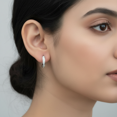 Close-up of a woman wearing a silver hoop earring against a neutral background