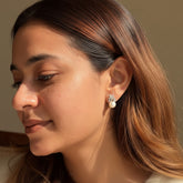 Close-up of a woman with long, wavy hair wearing 925 Sterling Silver Floral Pearl Studs