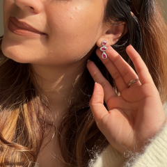 Close-up of a woman wearing a pair of 925 sterling silver earrings with a hand adjusting them.