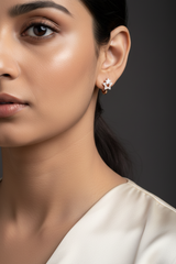 A close-up of a person's ear wearing a small star-shaped stud earring with a rose gold center and clear rhinestone-like accents.