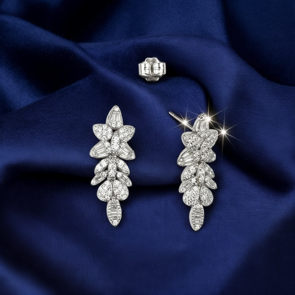 Silver leaf-shaped earrings on a blue fabric background