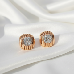 Rose gold earrings with diamond accents on a white fabric background