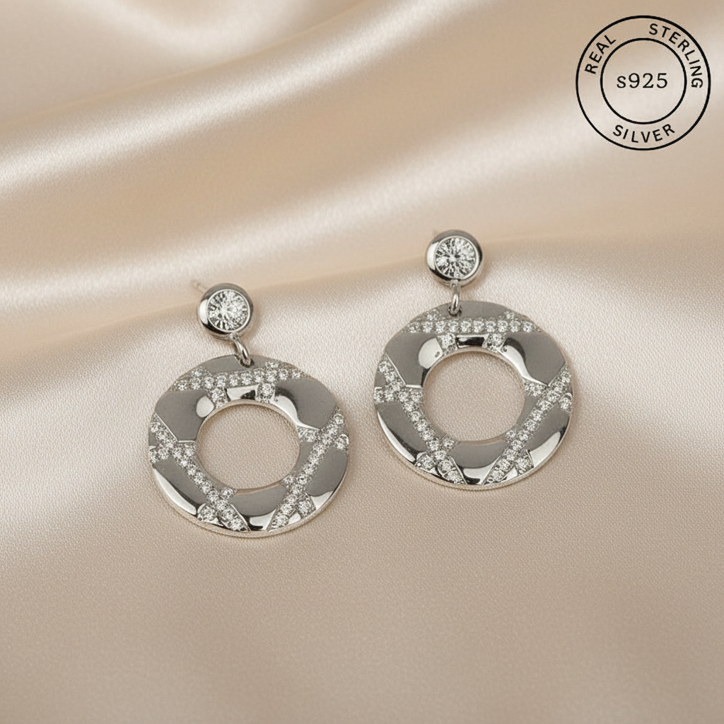 Silver earrings with circular design and embedded Zircons, featuring 'Real Sterling Silver' certification.