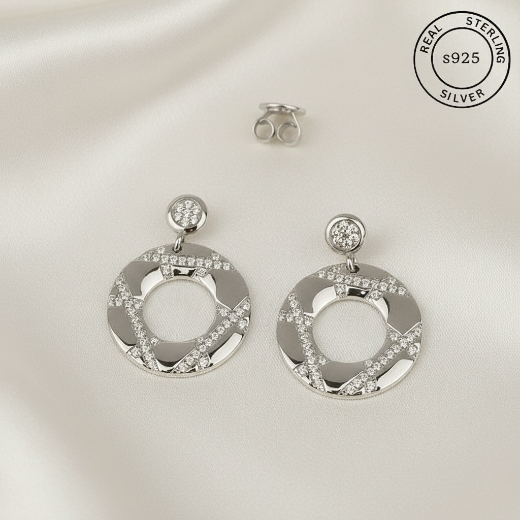 Silver earrings with circular design and embedded AAA+ CZ diamonds  featuring 'Real Sterling Silver' label.
