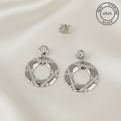 Silver earrings with circular design and embedded AAA+ CZ diamonds  featuring 'Real Sterling Silver' label.