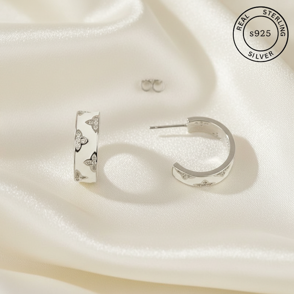 Silver hoop earrings with floral designs on a soft white fabric background, featuring 'Real Sterling Silver' stamp.