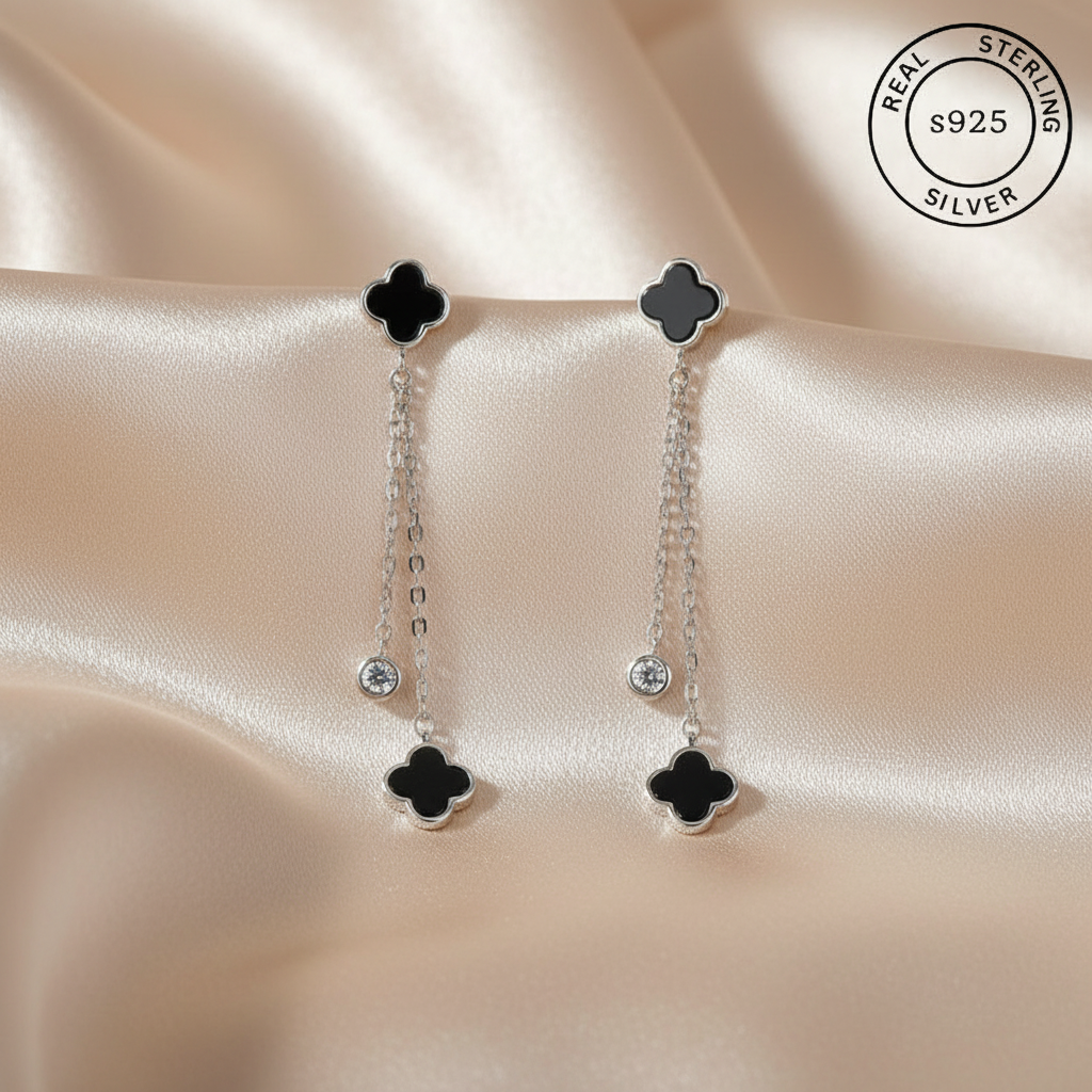 Pair of silver earrings with black clover-like designs  featuring 'Real Sterling Silver' certification.